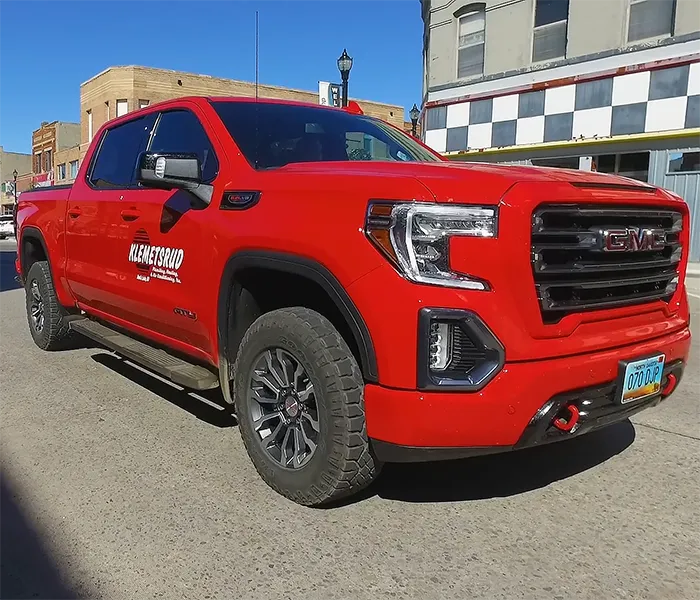 Klemetsrud Plumbing red truck driving down street.